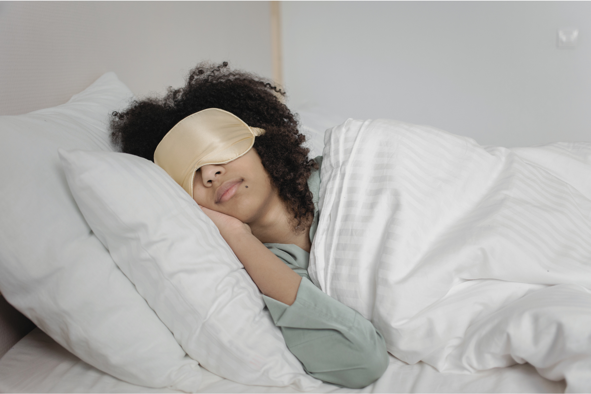 Woman sleeping peacefully in bed with an eye mask, supporting melatonin production.